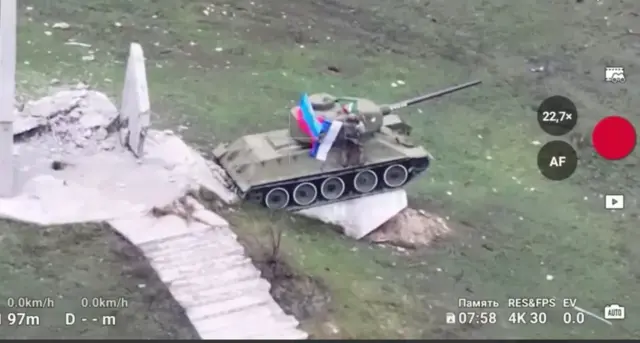 Военный на танке показывает российский флаг