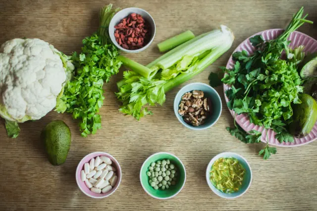 Compléments alimentaires biologiques à base de plantes et de minéraux en gélules, accompagnés de fruits et légumes frais.