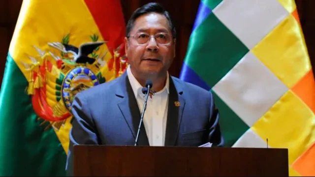 Luis Arce discursando, com bandeiras atrás