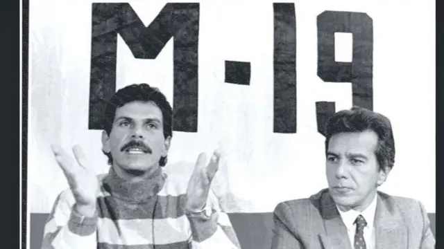 M-19 na powerful urban guerrilla wey enta conflict wit di Medellín Cartel for di 1980s. For dis foto, dia leader Carlos Pizarro Leongómez (left) discuss wit tori pipo di possible disarmament of di group for 1990.