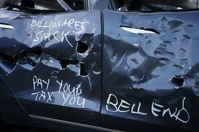 Hasar almış bir Tesla otomobilin üzerinde İngilizce vergini özde, milyarderler berbat ve güzel son yazıyor. 