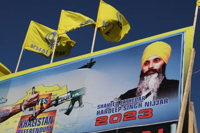 A mural features the image of late Sikh leader Hardeep Singh Nijjar, who was slain on the grounds of the Guru Nanak Sikh Gurdwara temple in June 2023, in Surrey, British Columbia, Canada 2023 ජුනි මාසයේදී ගුරු නානක් සික් ගුරුද්වාරා දේවාල භූමියේදී මරා දමන ලද සීක් නායක හර්දීප් සිං නිජ්ජාර්ගේ රූපය කැනඩාවේ බ්‍රිටිෂ් කොලොම්බියාවේ සරේ හි බිතු සිතුවමක දැක්වේ.