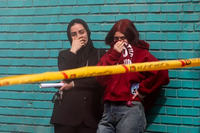 Xilasetmə işçiləri bu səhər tezdən hava hücumuna məruz qalan yaşayış binasının dağıntıları altında cəsədləri axtararkən mülki şəxslər üzlərini örtürlər.