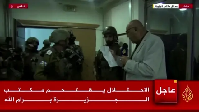 アルジャジーラの放送画面に、武装したイスラエル兵がアルジャジーラの従業員に閉鎖命令を渡している様子が映っている