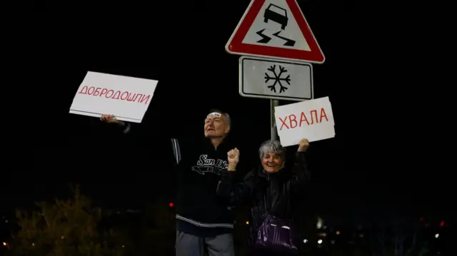 Stariji muškarac i žena sa transparentima dobrodošlice dočekuju studente