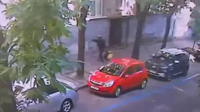 Чоловік у чорному з жовтим рюкзаком тримає витягнуту руку з пістолетом