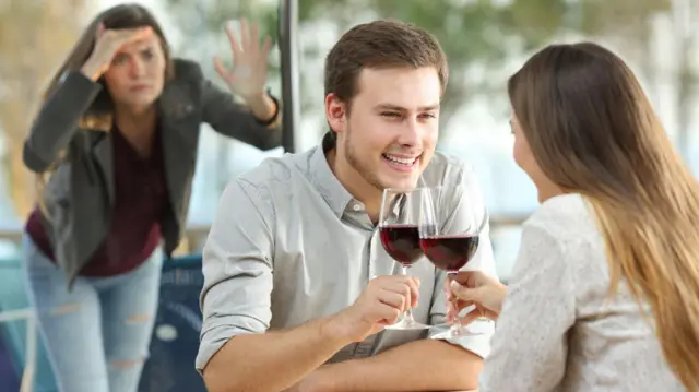 एक कपल किसी कमरे में वाइन पी रहा है और एक महिला बाहर से झांक रही है