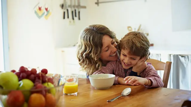 Ibu menyiapkan makanan dan memeluk anaknya. 