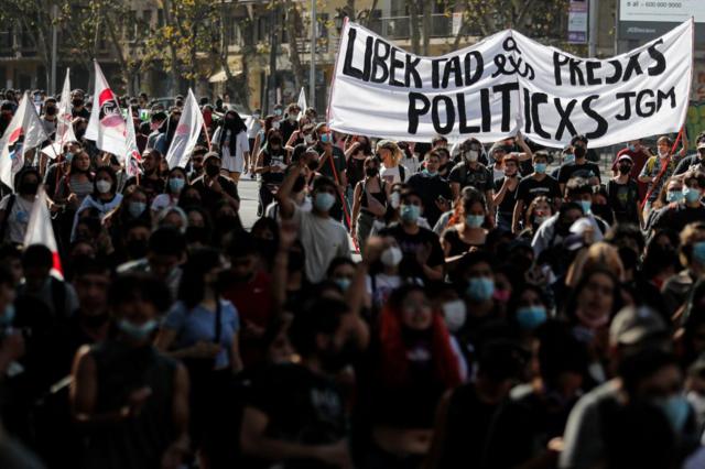 Pessoas carregam faixajogo ganhar dinheiro no pixmanifestação com o texto "Libertad a lxs presxs políticxs" 