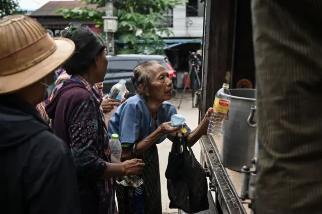People queue to buy cheap vegetable oil, in Yangon on August 18, 2022. - 