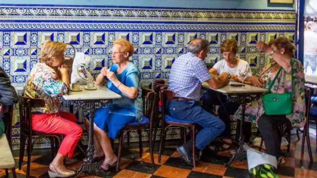 Dos grupos de personas de edad conversan en un bar de Bilbao. 