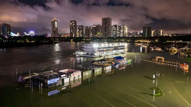 广西南部南宁市邕江码头附近，可见一条沿河步道及商店遭洪水淹没。
