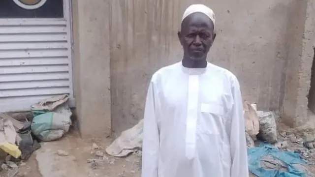 Nigerian local chief Musa Abdullahi dey wear traditional white gown and cap