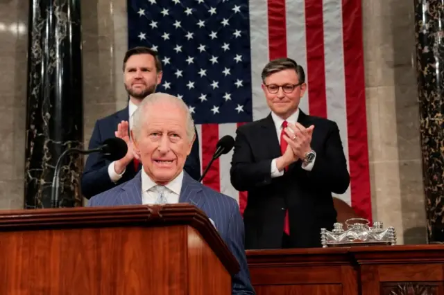 星条旗を背に立ち上がり拍手する米議会の二人と、その手前の演台を前に話す国王