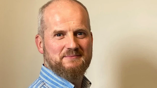 چهره پروفسور سم آدی به دوربین نگاه می‌کند