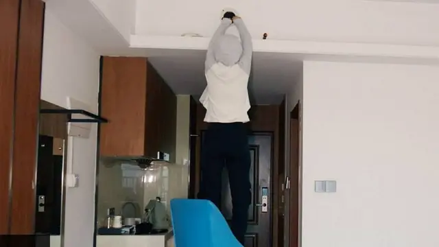 Un periodista de la BBC subido a una silla encuentra una cámara espía oculta en el ducto de ventilación de una habitación de hotel