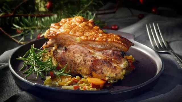 Кусок жареной свинины на блюде рядом с еловыми ветками