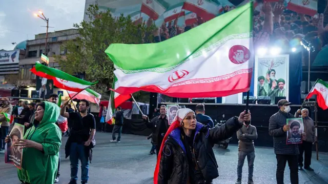 Люди размахивают флагами во время демонстрации в поддержку иранского правительства 22 марта 2026 года в центре Тегерана, Иран.