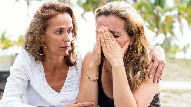 Mulher abraça outra, que está chorando
