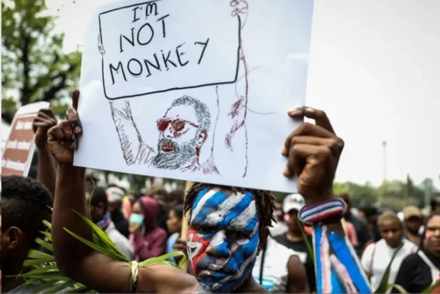 Seorang pria mengangkat poster yang bernada anti rasialisme.