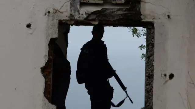 Imagem da silhueta de um policial armado. 