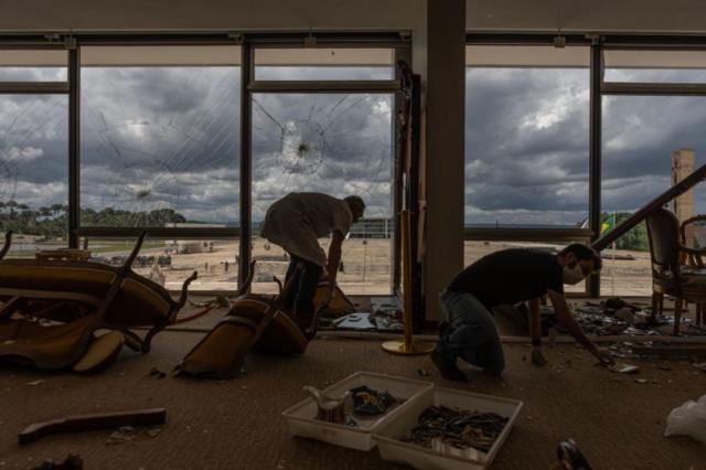 Fotografia colorida mostra funcionários recolhendo destroçosresultados bolão caixaprédio destruídoresultados bolão caixaatos golpistas