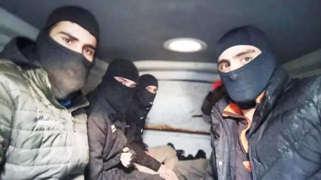 Bir grup maskeli adam kameraya bakıp poz veriyor