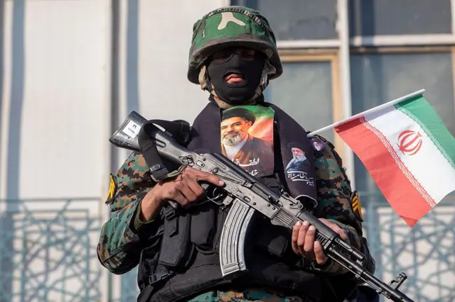 یک مامور امنیتی در ایران با عکس مجتبی خامنه‌ای