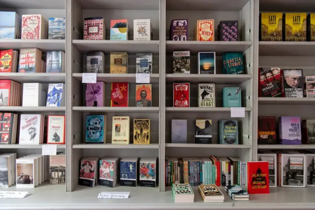 Книжкові полиці з англомовними та російськомовними виданнями. Окремо помітні книги про Росію, радянське минуле та Володимира Путіна, що підкреслює спеціалізацію книгарні на російській тематиці.