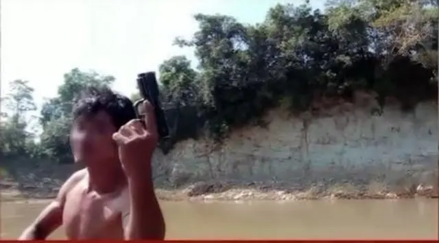 Seorang pria menunjukkan pistol saat mengantar WNI ke perbatasan Thailand-Myanmar.