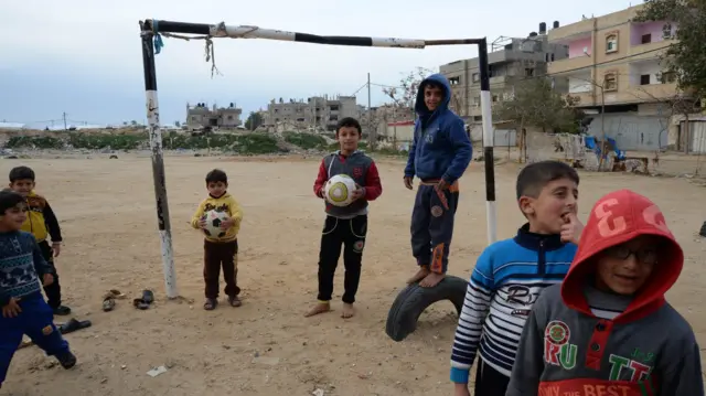 Crianças segurando bolas em campo de futebol de terra batida no bairro Brasil em 2015