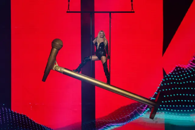 жена стоји на великом микрофону на сцени