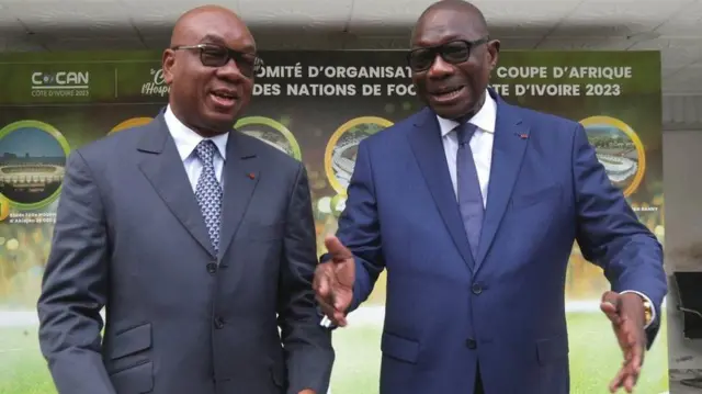 رئیس فدراسیون فوتبال ساحل عاج، ادریس دیالو (چپ) و رئیس کمیته سازماندهی مسابقات، فرانسوا آمیچیا (راست) به شدت درگیر آماده سازی ساحل عاج برای جام ملت‌های آفریقا ۲۰۲۳ بوده‌اند