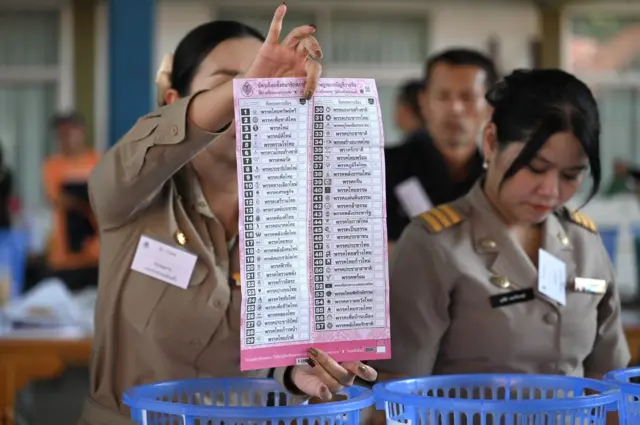 ในระหว่างการเปิดหีบขึ้นมานับคะแนนเลือกตั้งใหม่ ของเขตเลือกตั้งที่ 7 จ.ปทุมธานี เมื่อ 19 ก.พ. ตามมติ กกต. เจ้าหน้าที่บางคนได้จับบัตรในลักษณะที่นิ้วปิดบังบาร์โค้ดบนบัตรเลือกตั้ง สส.แบบบัญชีรายชื่อ