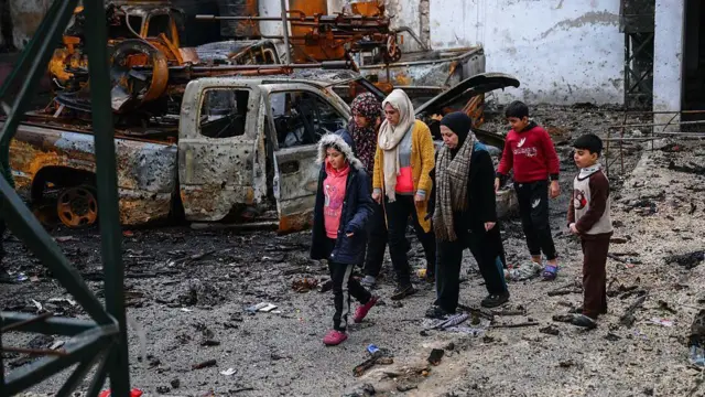 Halep'teki çatışmalar sonrası harabeye dönmüş sokaklar ve yanmış arabaların arasından yürüyen siviller 