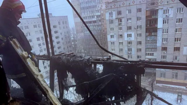 Спасатель стоит на поврежденном балконе многоэтажного дома