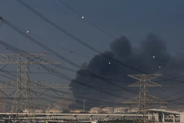 На дальнем плане видны портовые строения, над ними клубится дым