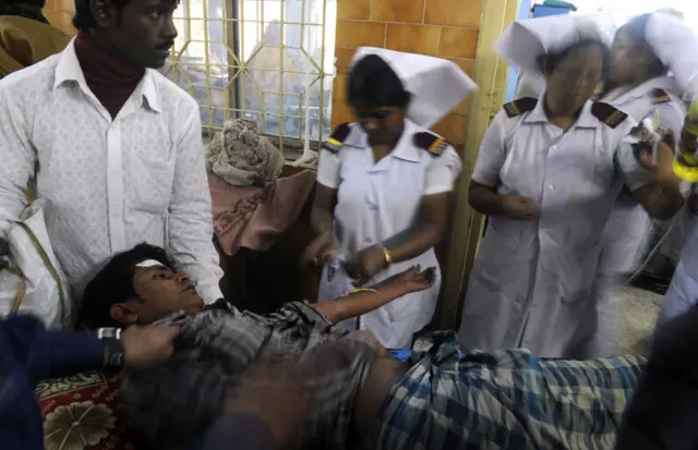 Mwathiriwa amelala chali huku mkono wake ukiwa umenyooshwa huku wataalamu wa afya wakimhudumia katika hospitali ya Diamond Harbour katika Bandari ya Diamond, Kolkata, tarehe 15 Desemba 2011.