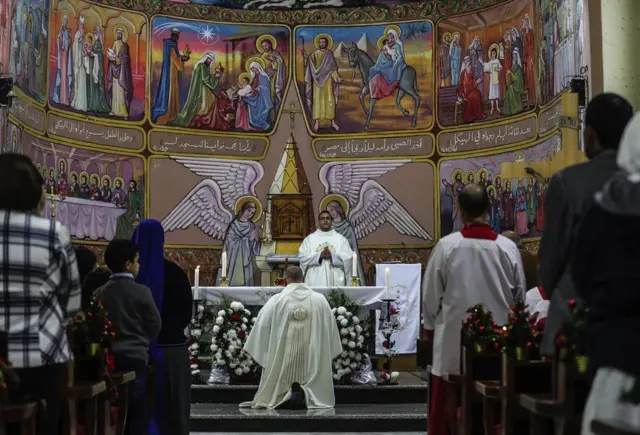 Um padre realiza uma cerimônia na vésperacasino 440Natal enquanto as pessoas rezamcasino 440frente a uma parede decorada com cores vivas que retrata cenas cristãs dentro da Igreja Católica da Sagrada Família, na cidadecasino 440Gaza,casino 44024casino 440dezembrocasino 4402018