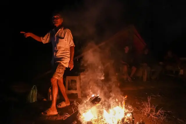 Sejumlah warga menyalakan api unggun di salah satu sudut pusat kota Kuala Simpang yang gelap akibat jaringan listrik belum pulih di Kabupaten Aceh Tamiang, Aceh, Selasa (9/12/2025).