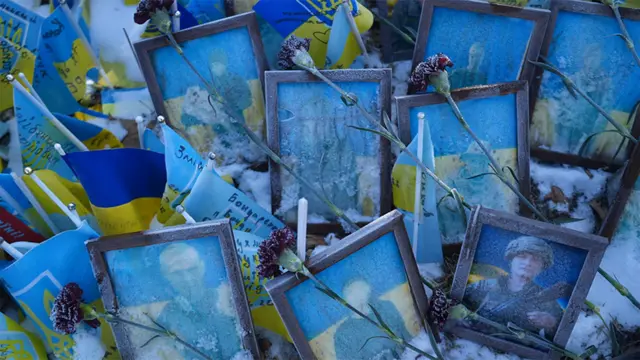 Fotografias emolduradas de soldados ucranianos, com flores espalhadas na frente deles