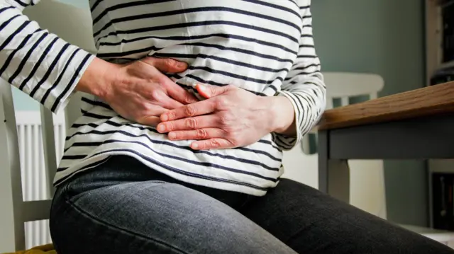 Braçosbetnacional betnacionalmulher segurando a barriga, indicando dor