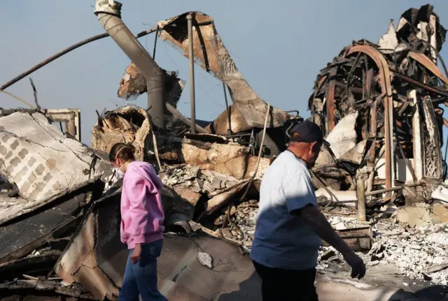 Unos vecinos pasean por las zonas afectadas por los incendios.