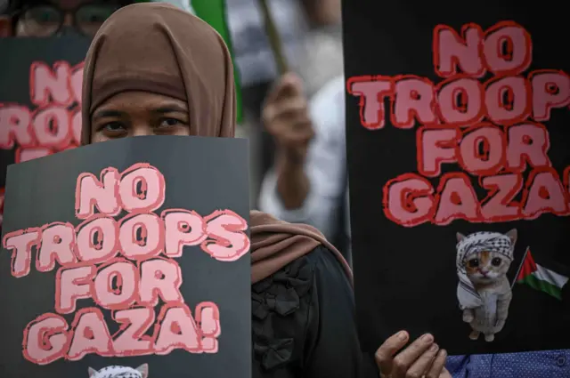 Seorang peserta aksi dari Aliansi Mahasiswa dan Masyarakat Sipil membawa poster saat aksi di depan Gedung DPR RI, Jakarta, Jumat (6/3/2026). Dalam aksinya, mereka mengecam serangan Amerika Serikat dan Israel terhadap Iran karena dinilai melanggar hukum internasional dan kedamaian dunia serta meminta pemerintah untuk mengevaluasi kesepakatan Indonesia dalam piagam Board of Peace (BoP) karena dianggap tidak sesuai yang dimandatkan Dewan Keamanan PBB 2803. 