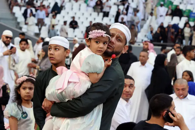 رجل يحمل طفلة بعد أداء صلاة عيد الفطر في استاد المدينة التعليمية بالريان، قطر