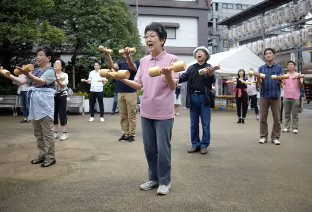 Idosos se exercitando no pátio de um templo em Tóquio