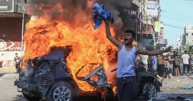 Un garçon palestinien réagit devant une voiture israélienne en feu saisie par des militants et emmenée à Gaza samedi.