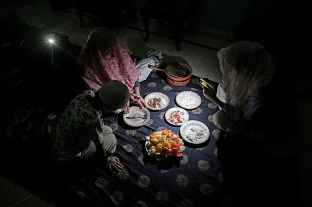 family eating dinner in the light of a mobile phone in Islamabad