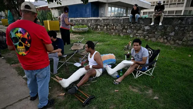 Pessoas feridas com as pernas engessadas permanecem no lado externo do hospital Domingo Luciani de Caracas, no dia 25 de junho de 2026, após os dois terremotos que sacudiram a capital venezuelana