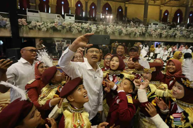 Menteri Sosial Saifullah Yusuf (tengah) berswafoto dengan murid dan guru saat pra peluncuran Sekolah Rakyat dan doa bersama untuk Sumatera di Graha Unesa, Surabaya, Jawa Timur, Senin (29/12/2025).
